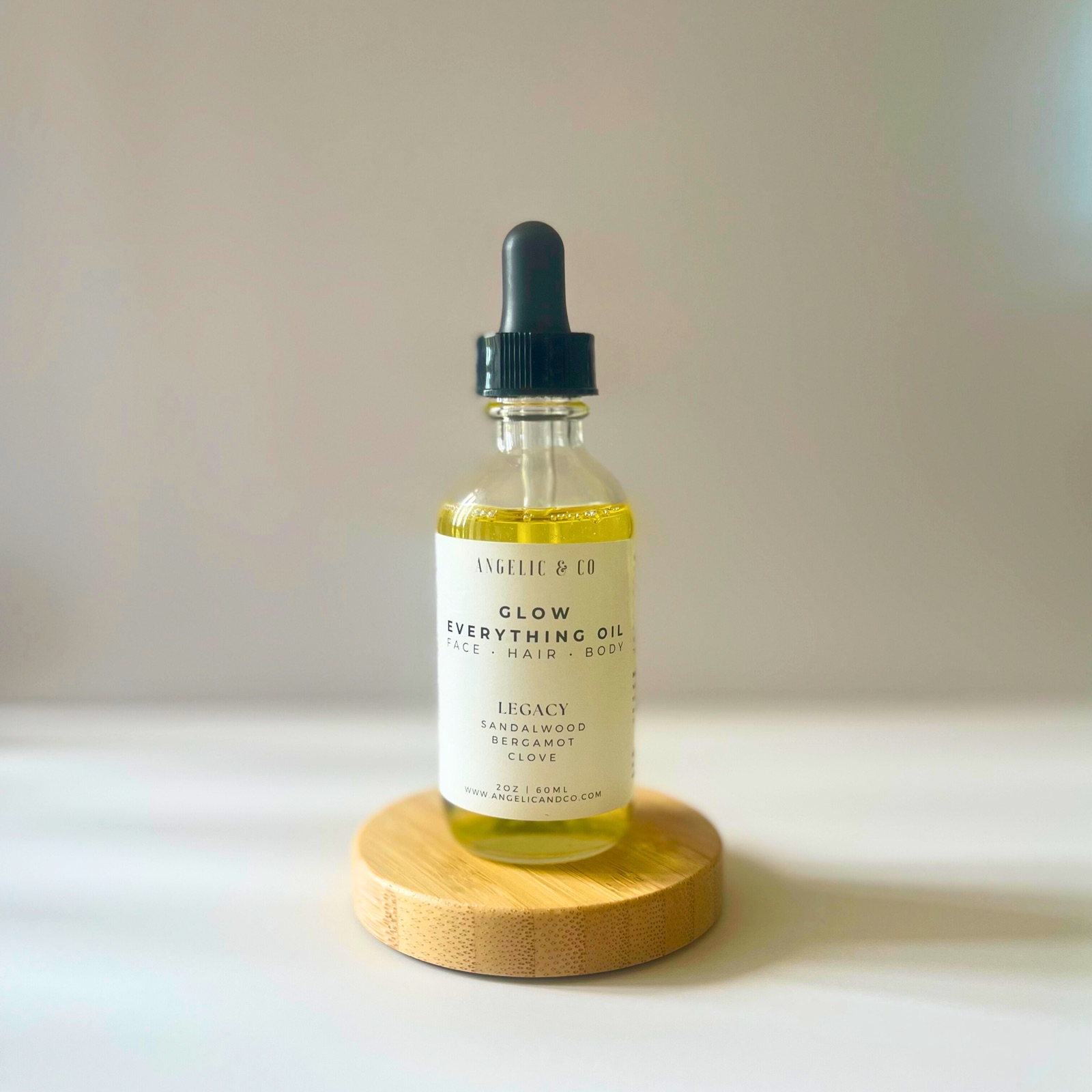 A bottle of Angelic & Co. Glow Everything Oil on a wooden coaster