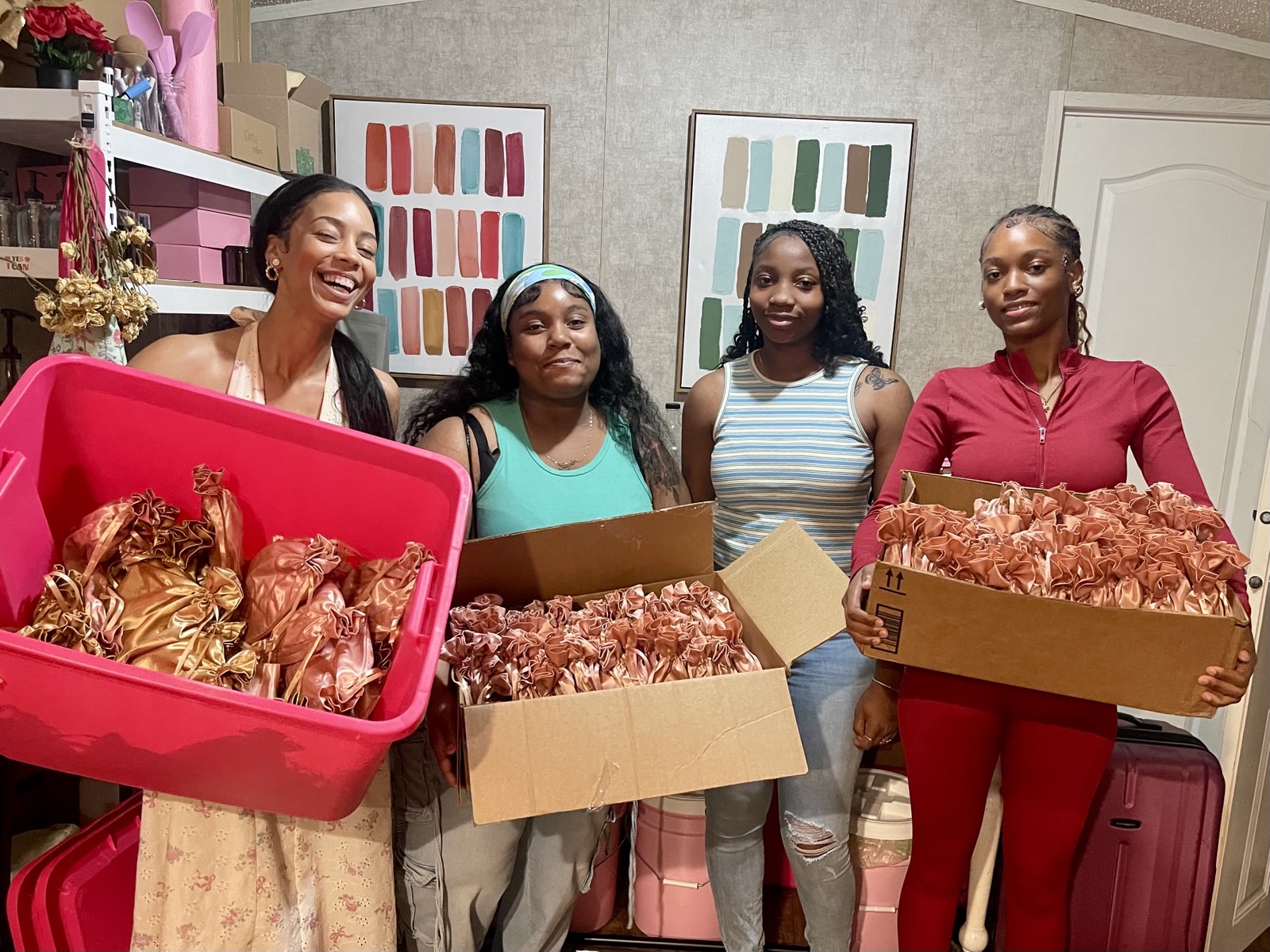 Ella and three young women holding bins and boxes of packaged products